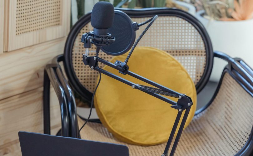 pexels-photo-6953870-6953870 Modern laptop and microphone on tripod placed near wicker chair in modern studio before recording podcast
